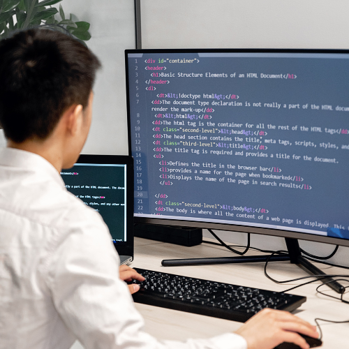 A CodeXpress developer writing HTML and CSS code on a dual-monitor setup